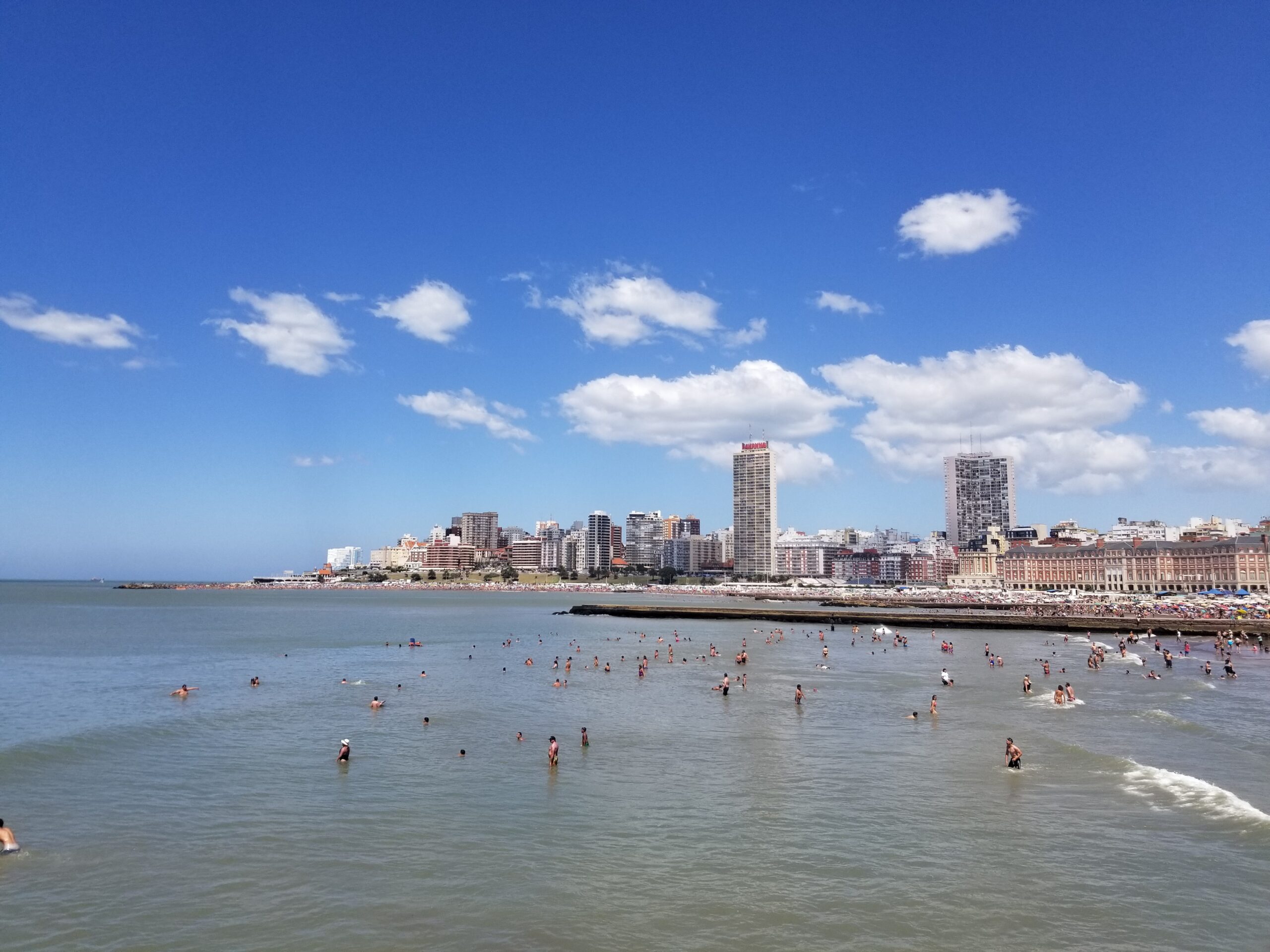 Beach in Mar del Plata with people in the water and the city skyline behind
